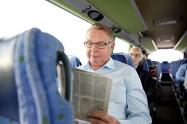 happy senior man reading newspaper on coach